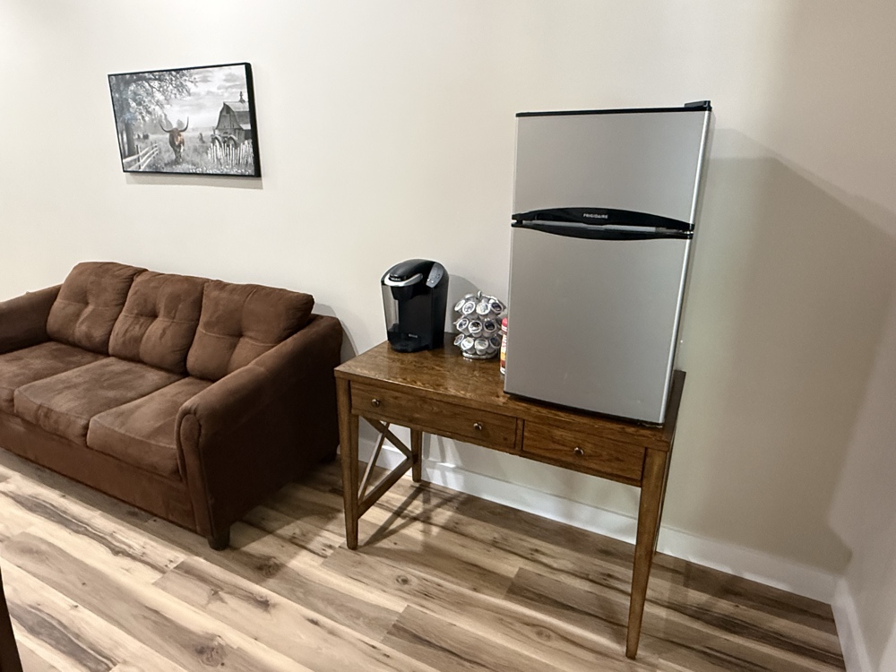small refrigerator and coffee maker as well as comfy indoor seating